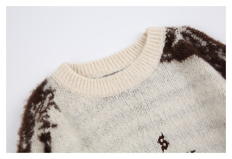 Close-up of an ivory sweater's ribbed crew neck, dark brown patterned shoulders, and partial chest emblem.
