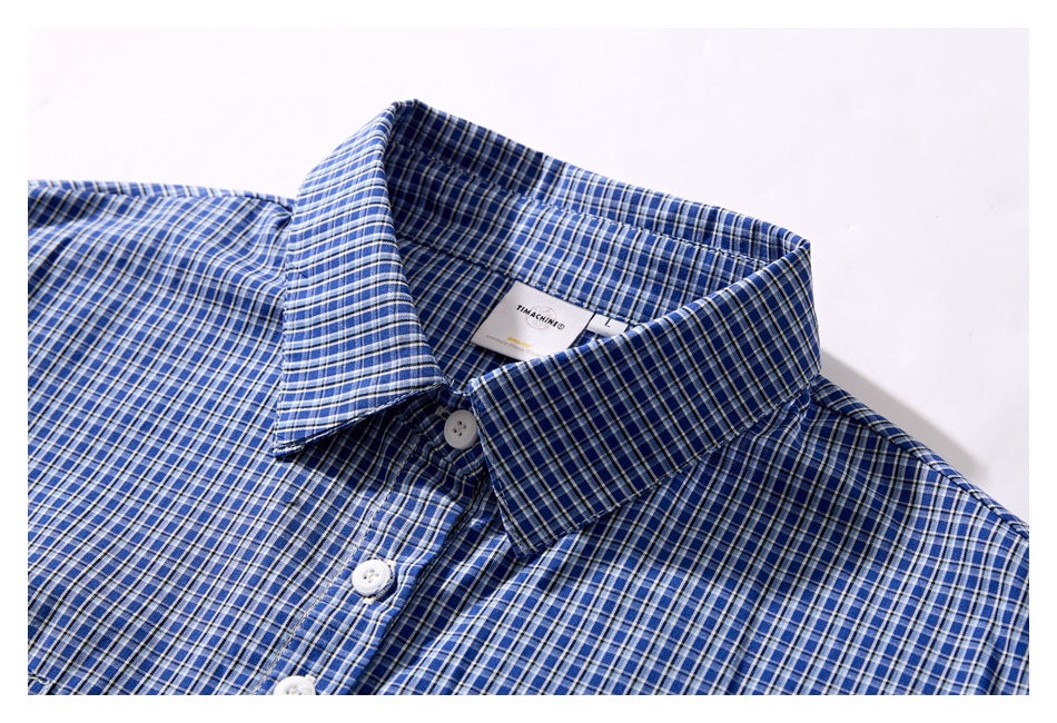 Close-up of the blue plaid shirt collar and button placket on a white background.