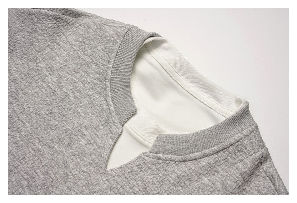 Close-up of a gray textured sweatshirt neckline with ribbed trim and a white inner layer.