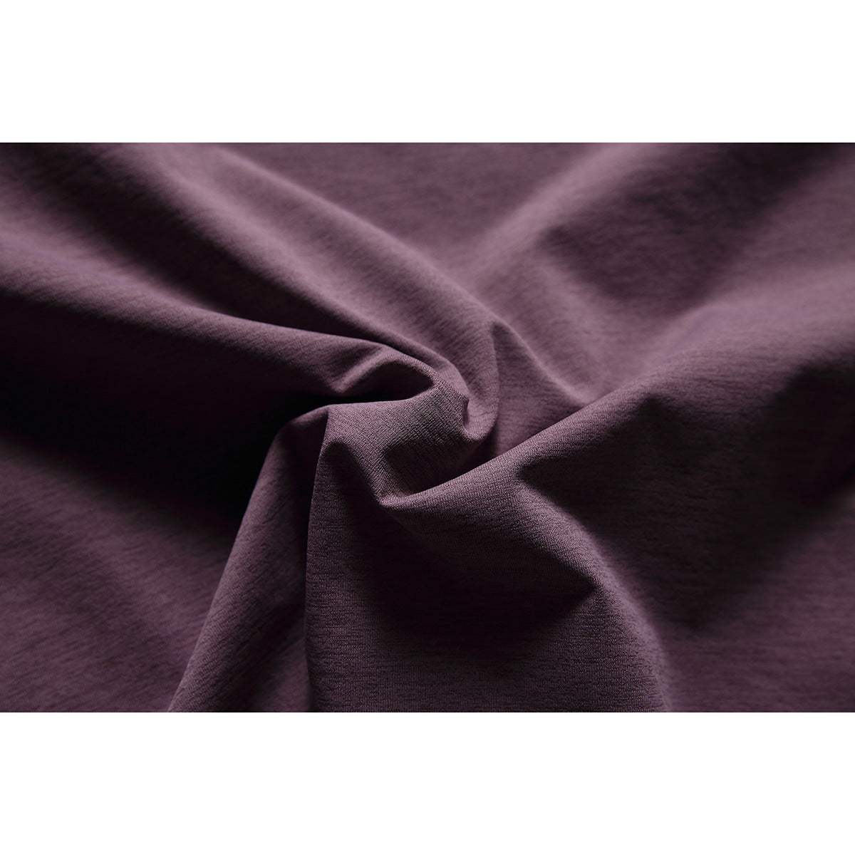 Macro view of dark plum fabric gathered into folds, showing its fine surface texture.