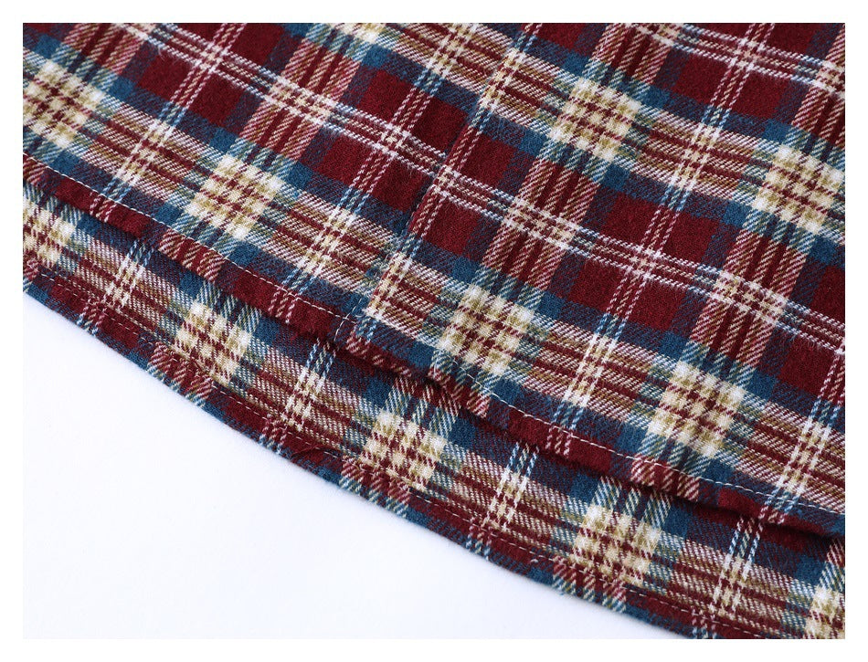 Close-up of the stitched hem on a burgundy, navy, cream, and tan plaid shirt.