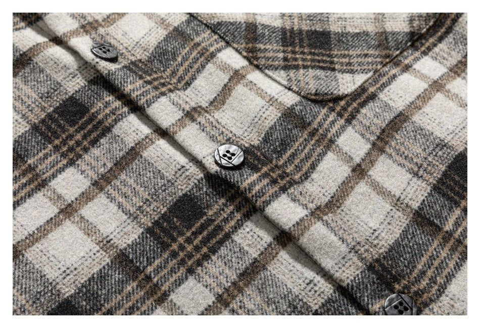 Close-up of a beige, gray, and brown plaid garment with dark buttons and a pointed collar.