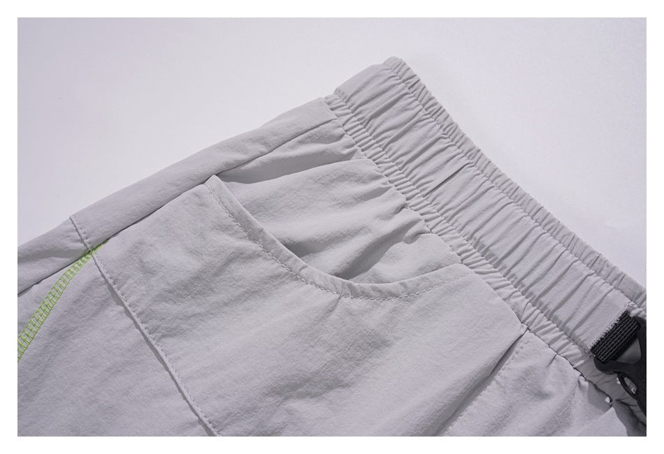 Close-up of the gray skirt's elastic waistband, curved pocket, panel seam, and lime stitching.