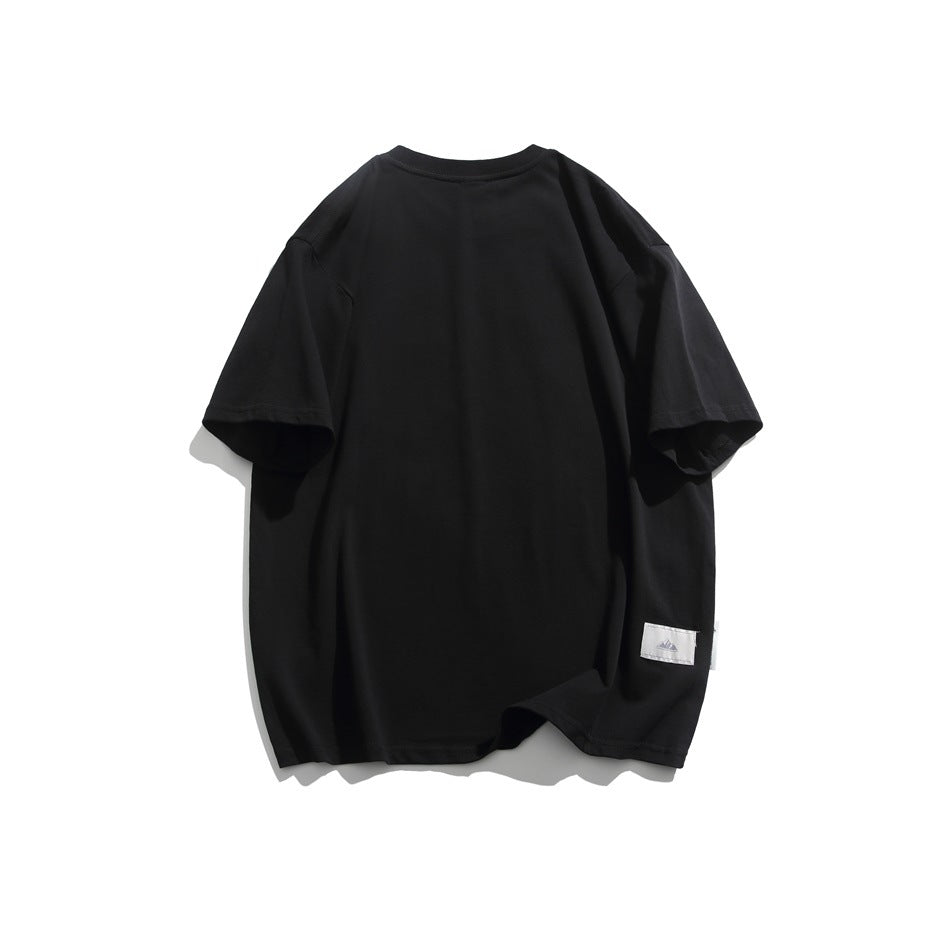 Back view of a plain black oversized short-sleeve T-shirt with a small sewn patch near the hem.