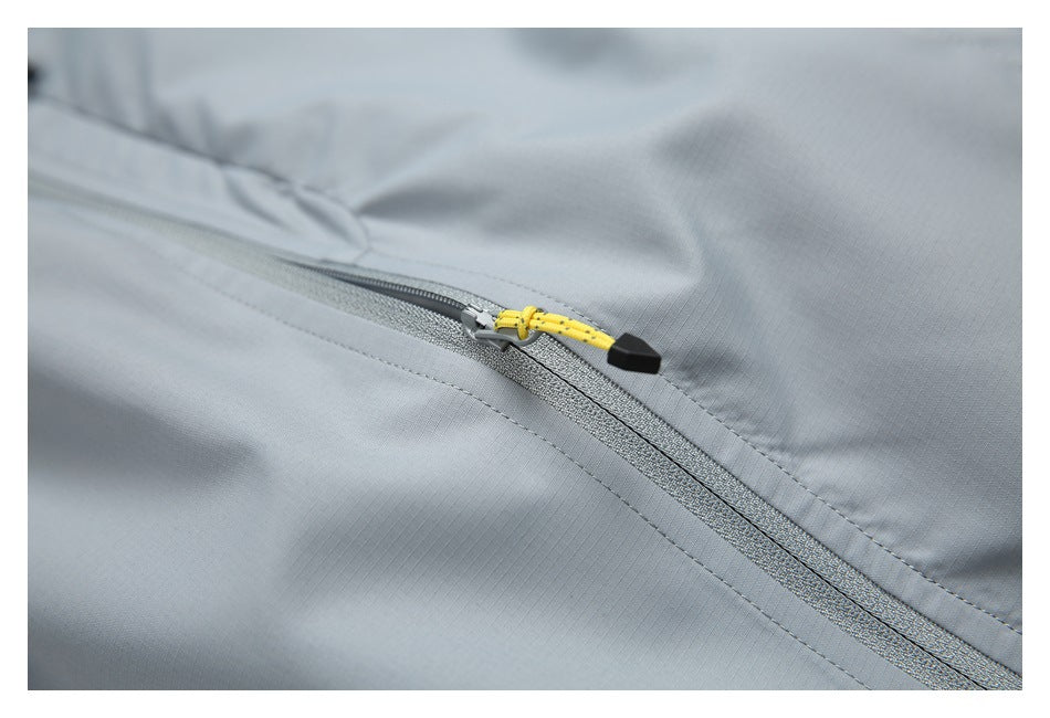 Close-up of a gray jacket zipper with a bright yellow cord pull and black end cap.