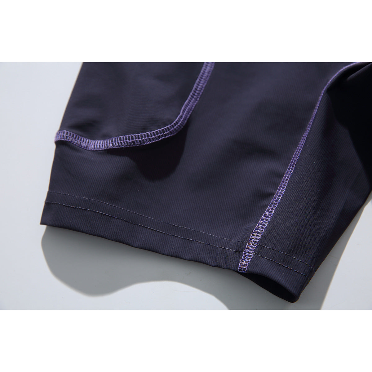 Close-up of the dark navy shirt's hem and purple overlock stitching.