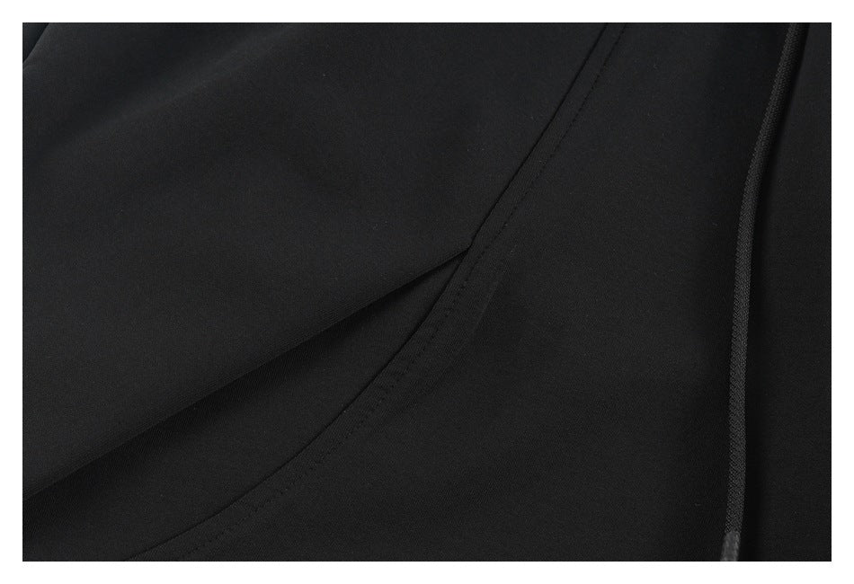 Close-up of black pants showing a stitched seam and the drawstring along the side.