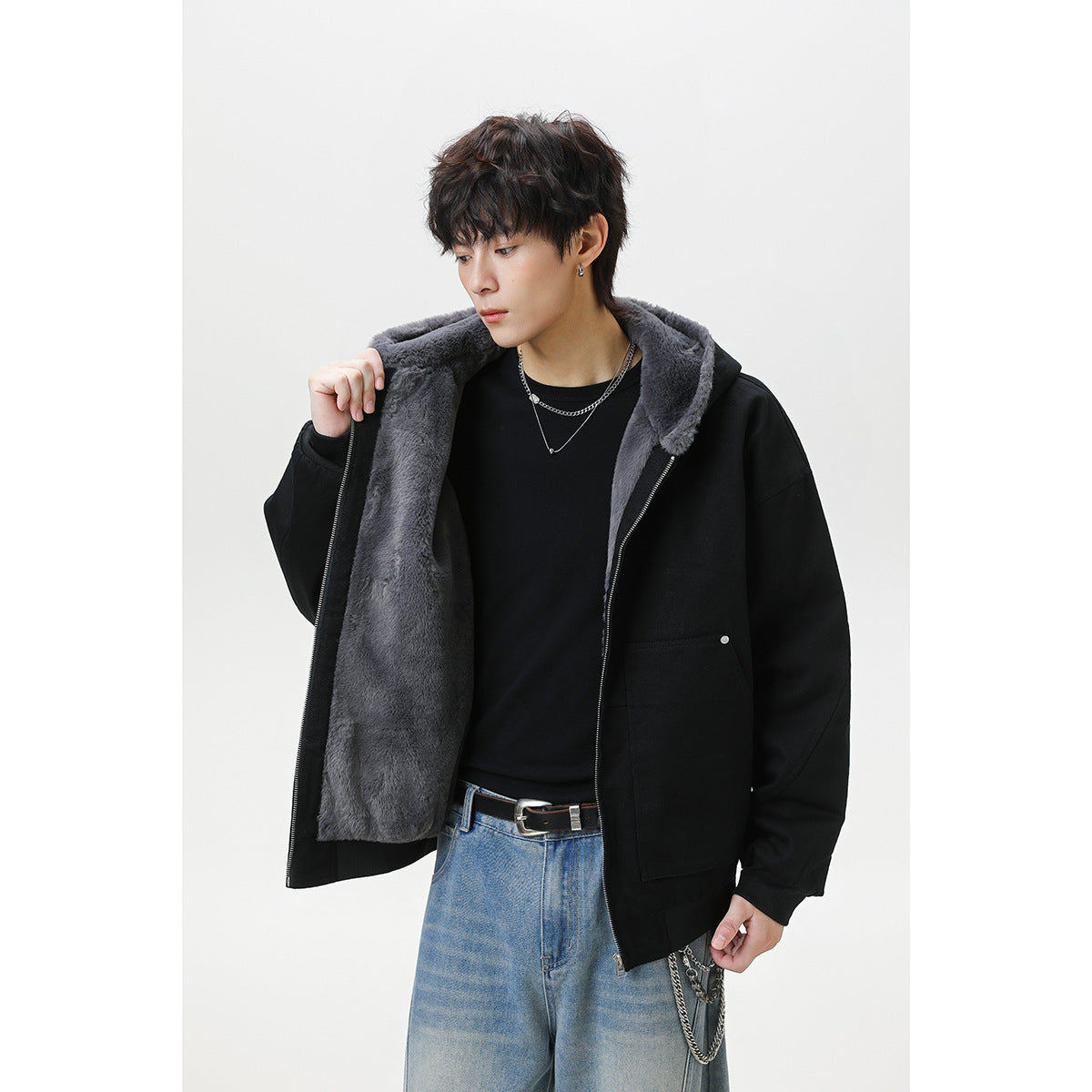 Model holding open a black hooded jacket to show its gray plush lining and large front pockets.