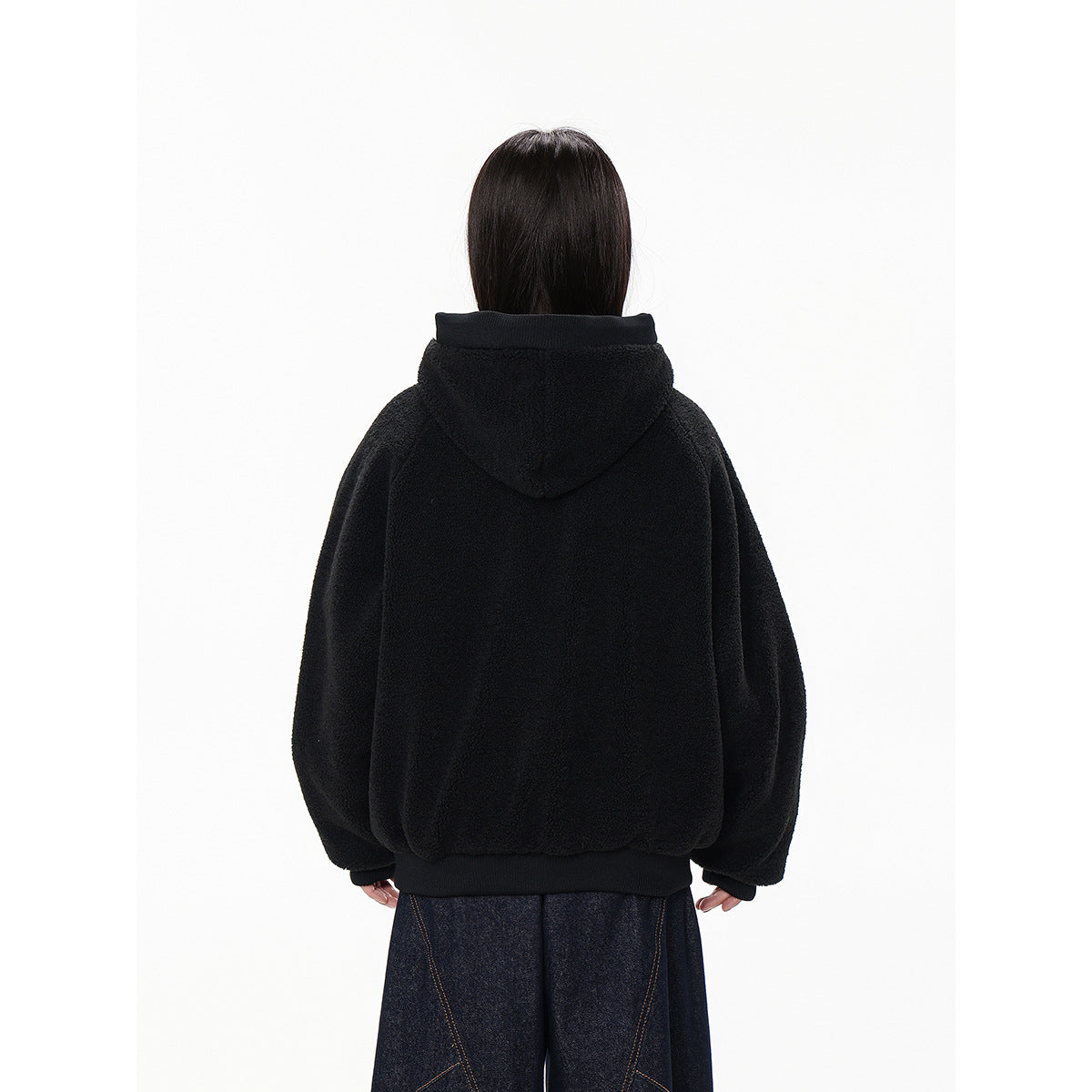 Back view of a model wearing a black hooded jacket with a ribbed hem and cuffs.