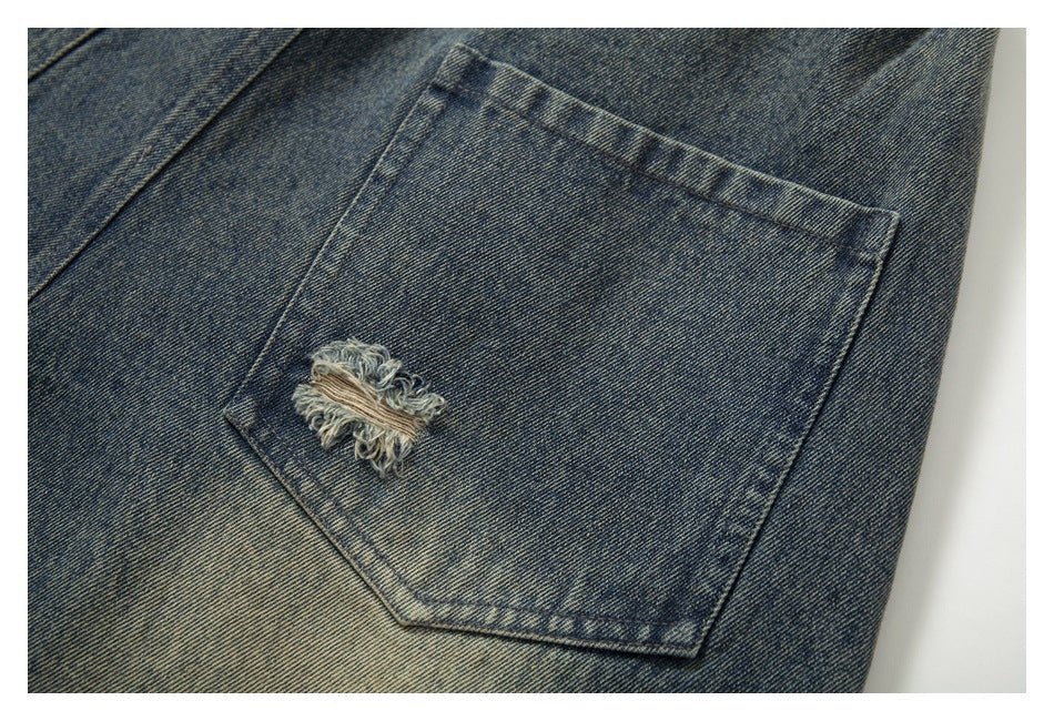 Close-up of a distressed rear pocket on faded dark blue denim jeans.