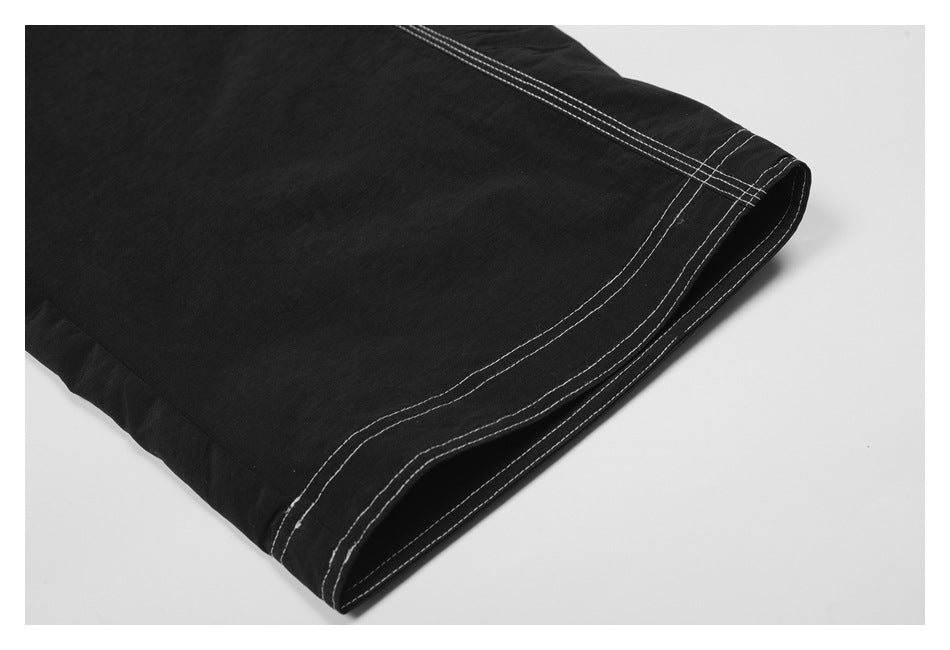 Close-up of a black trouser leg hem with several rows of white stitching.