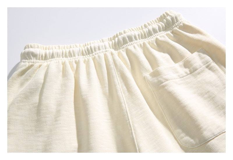 Close-up of cream pants showing the gathered elastic waistband and a large patch pocket.