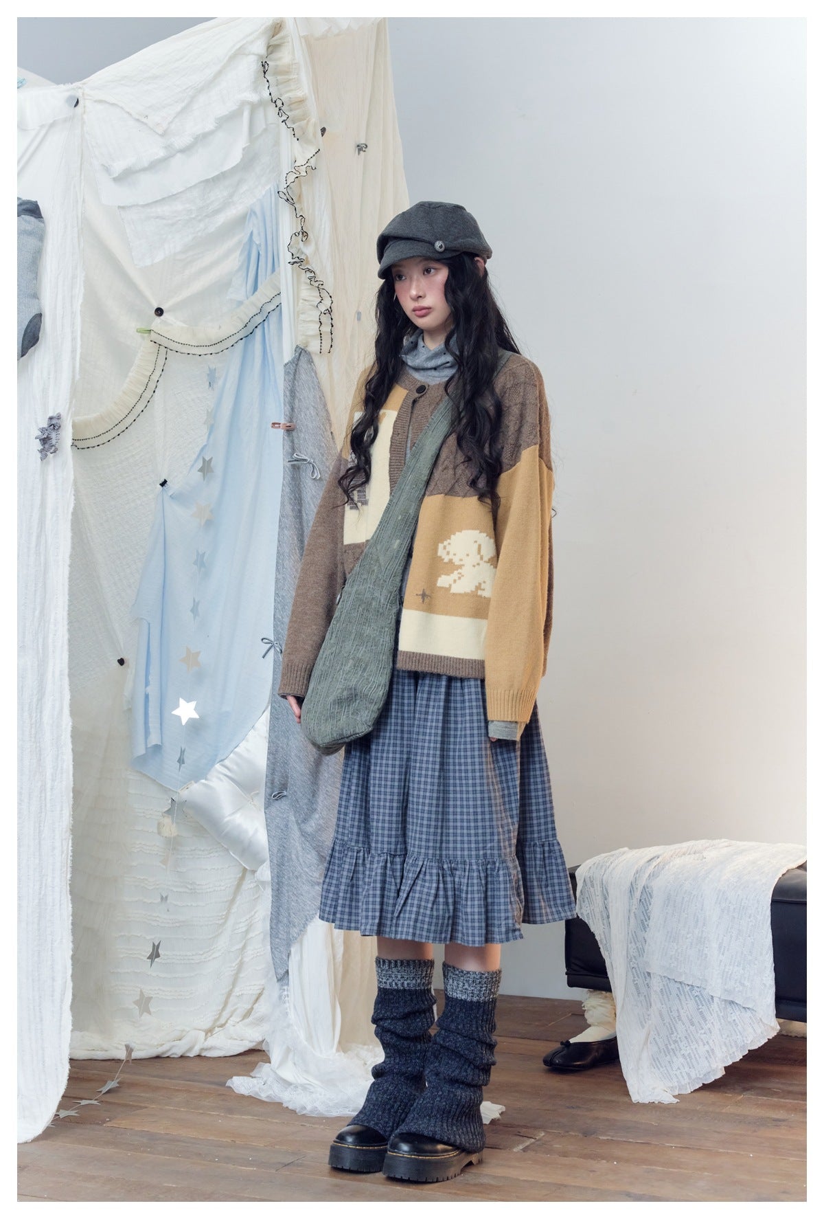Model in the color-block cardigan with a crossbody bag, plaid skirt and chunky boots, turned slightly to the side