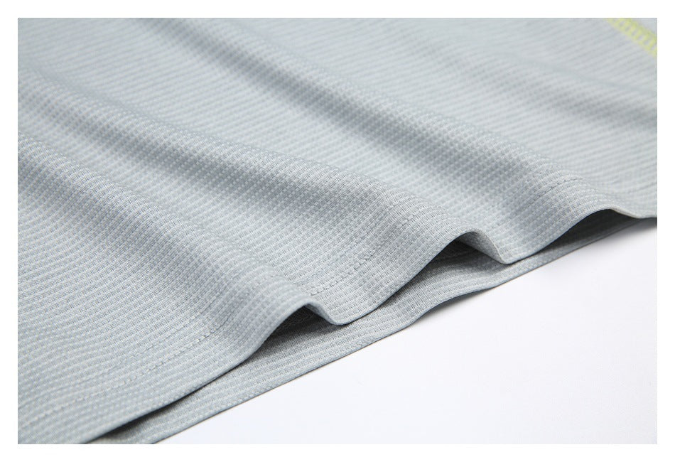 Close-up of softly folded pale gray textured shirt fabric with a small section of yellow stitching.