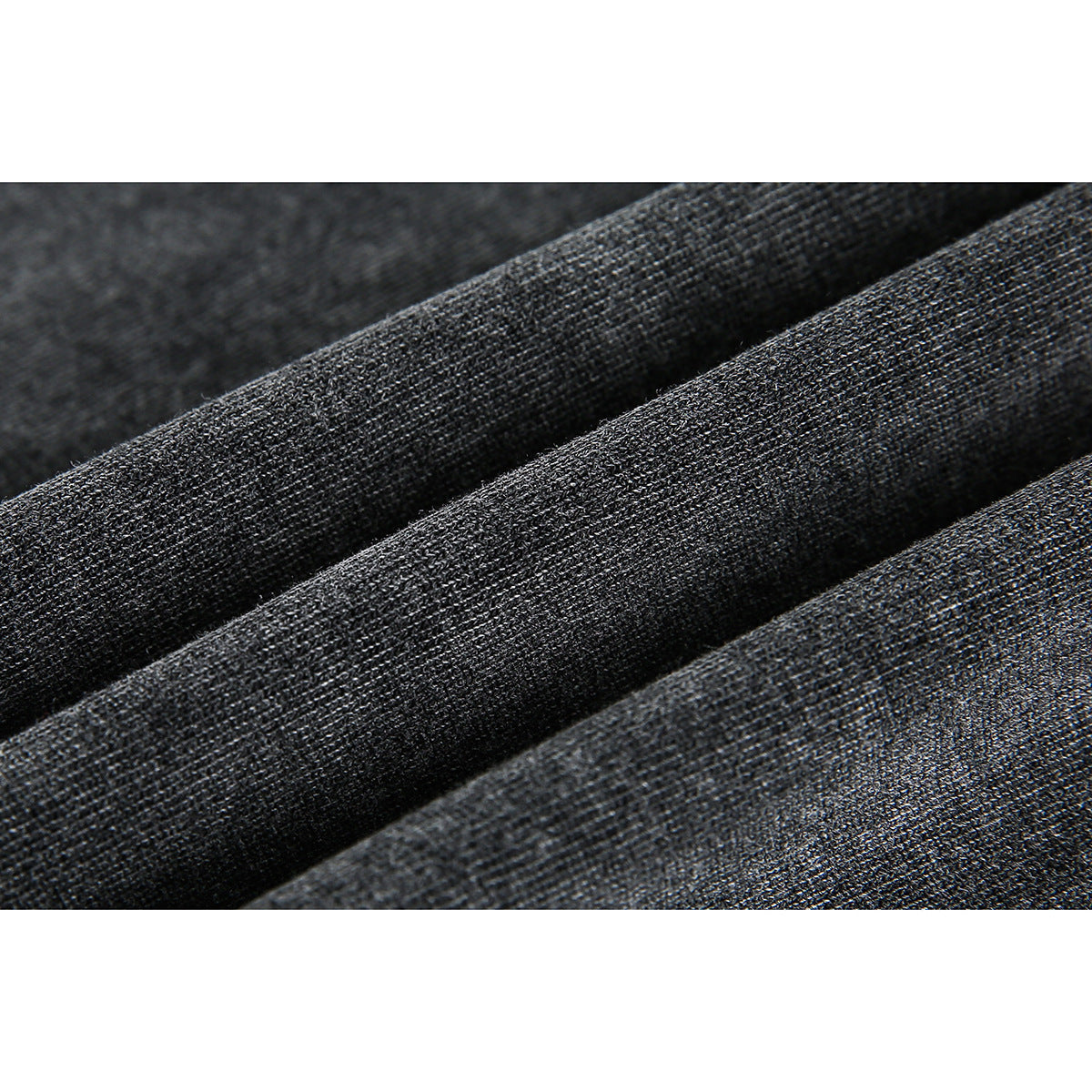 Macro view of dark charcoal fabric arranged in soft folds, showing its fine surface texture.