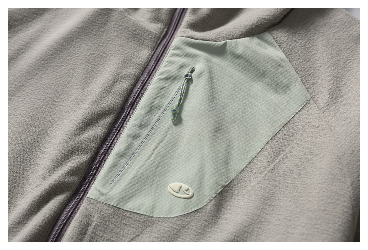 Close-up of a gray fleece jacket with a pale green zippered chest pocket and a small oval patch.