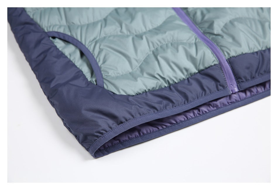 Close-up of a blue-gray quilted garment hem with navy panels and purple trim.