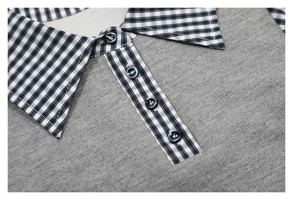 Close-up of a gray knit shirt with a black-and-white plaid collar and button placket.