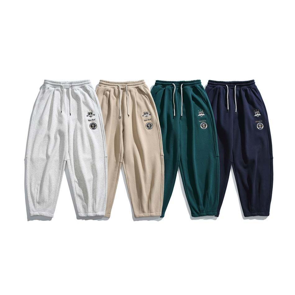 Four pairs of relaxed joggers shown together in light gray, beige, deep teal, and navy.