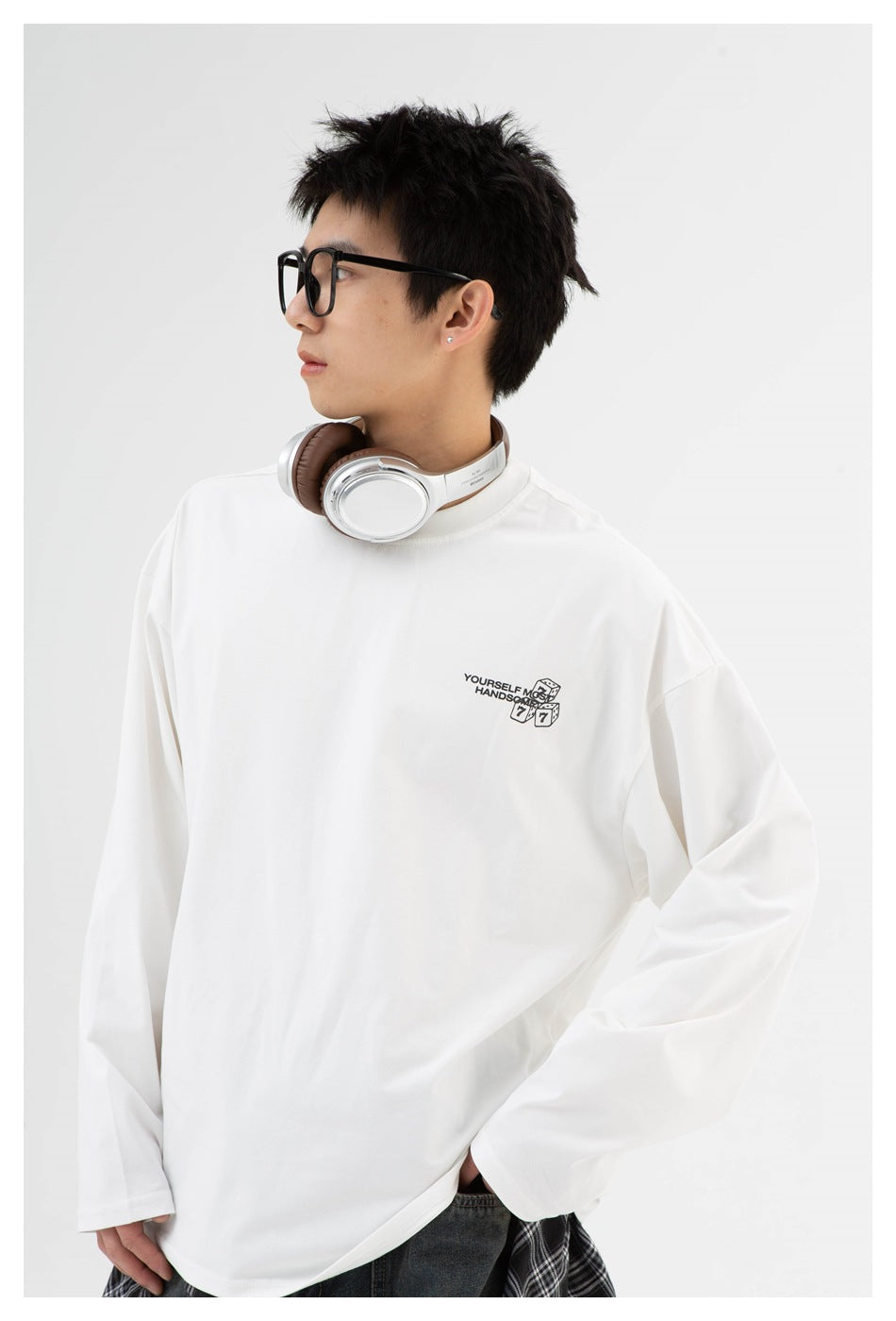 Angled front view of a model wearing an oversized white long-sleeve shirt with a small chest graphic.