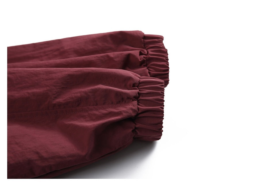 Close-up of two elasticated cuffs on a burgundy garment.