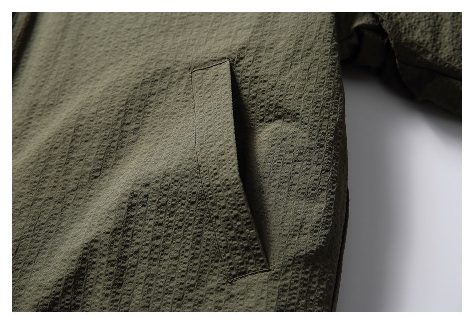 Close-up of a vertical welt pocket on the olive jacket.