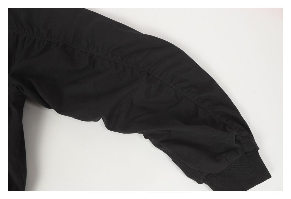 Close-up of a black garment sleeve showing a curved seam and ribbed cuff on a light background.
