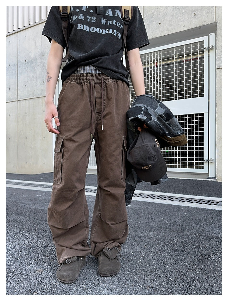 Model wearing loose brown cargo pants with an elastic drawstring waist and flap pockets on both legs.