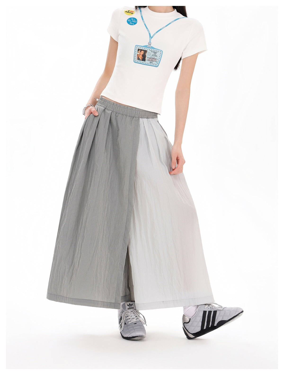 Model wearing gray grid-patterned and white panelled wide-leg bottoms with an elastic waist and a white graphic T-shirt.