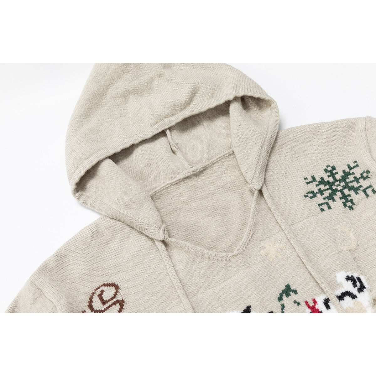 Close-up of a cream knit hooded sweater with drawstrings and green, brown, and multicolor motifs.