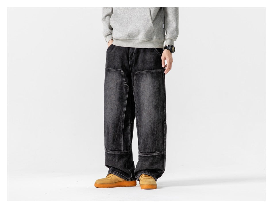 Model wearing black washed wide-leg jeans with a gray hoodie and tan sneakers, front view, cropped at the torso