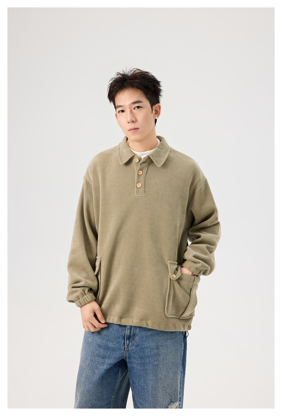 Model wearing an oversized olive collared pullover with buttoned flap pockets and blue jeans.