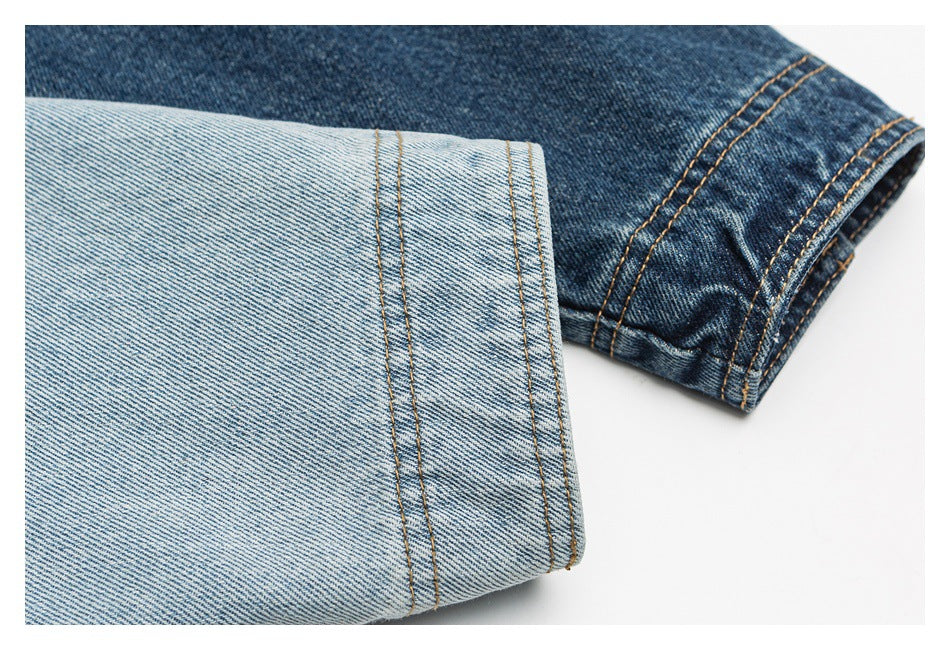 Close-up of light- and dark-wash denim jacket fabric with contrasting topstitching and finished edges.