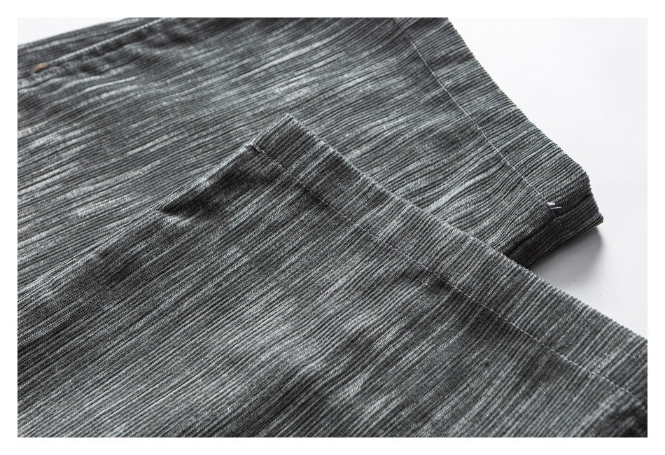 Close-up of gray striped trousers showing overlapping fabric panels and stitched seams.