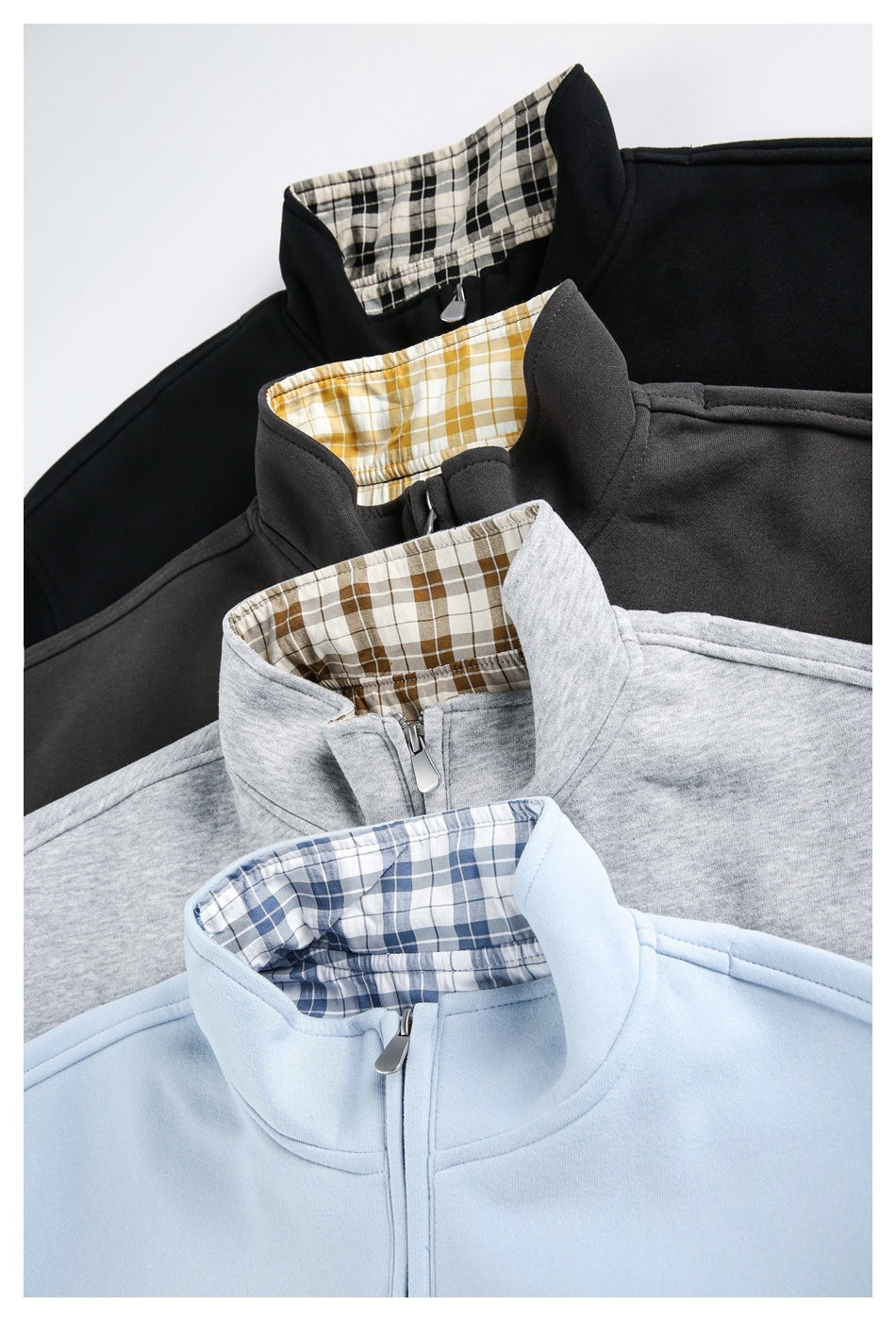 Four zip-front high-collar jackets in black, charcoal, heather gray, and pale blue, with plaid inner collars.