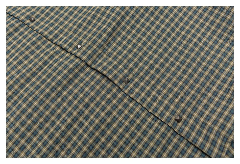 Close-up of the button placket on a blue, tan, and cream plaid shirt.