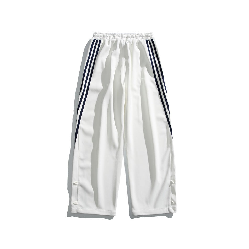 Front view of white wide-leg track pants with an elastic waistband and three dark side stripes on each leg.