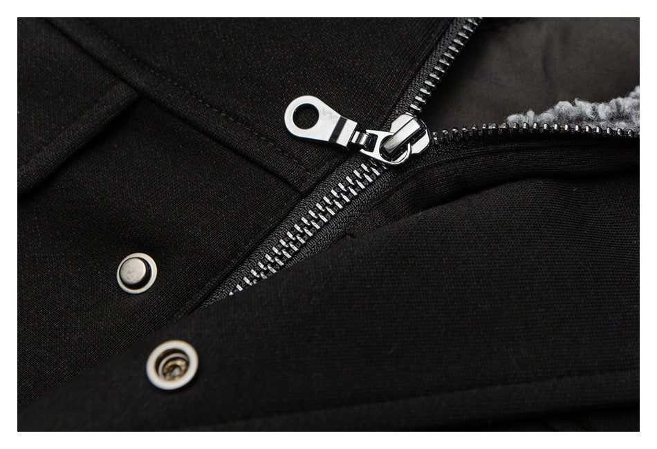 Close-up of a black garment's silver zipper pull and metal snap fasteners, with gray lining visible.