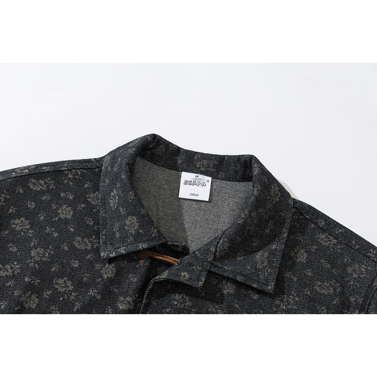 Close-up of a dark charcoal floral-patterned jacket collar with a sewn neck label.