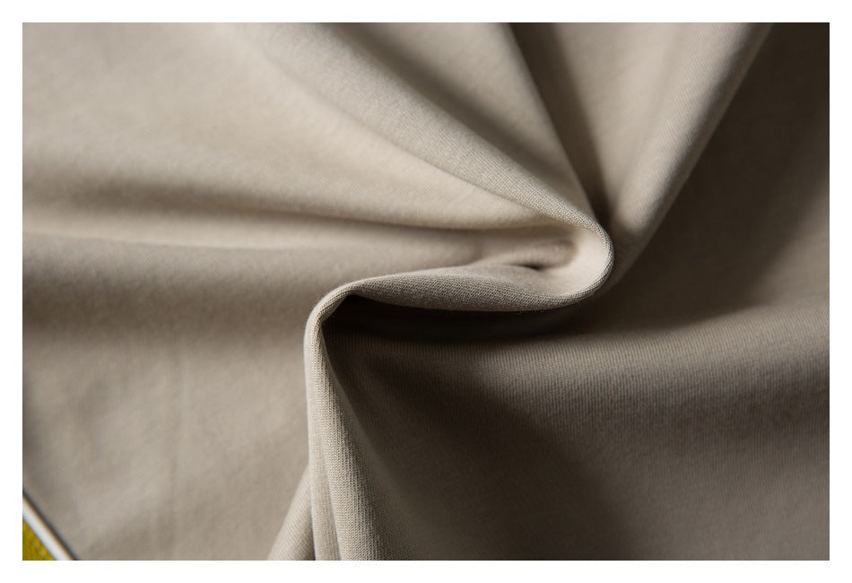 Close-up of smooth taupe fabric draped into folds, showing its subtle surface texture.