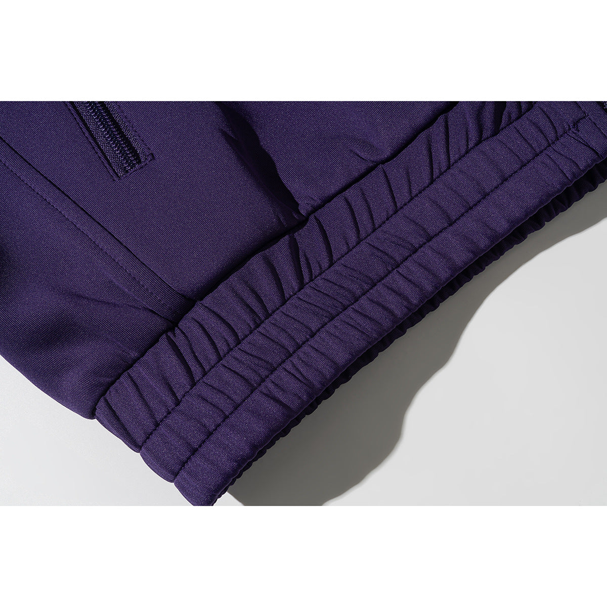 Close-up of a purple jacket's zip pocket and gathered elastic hem.