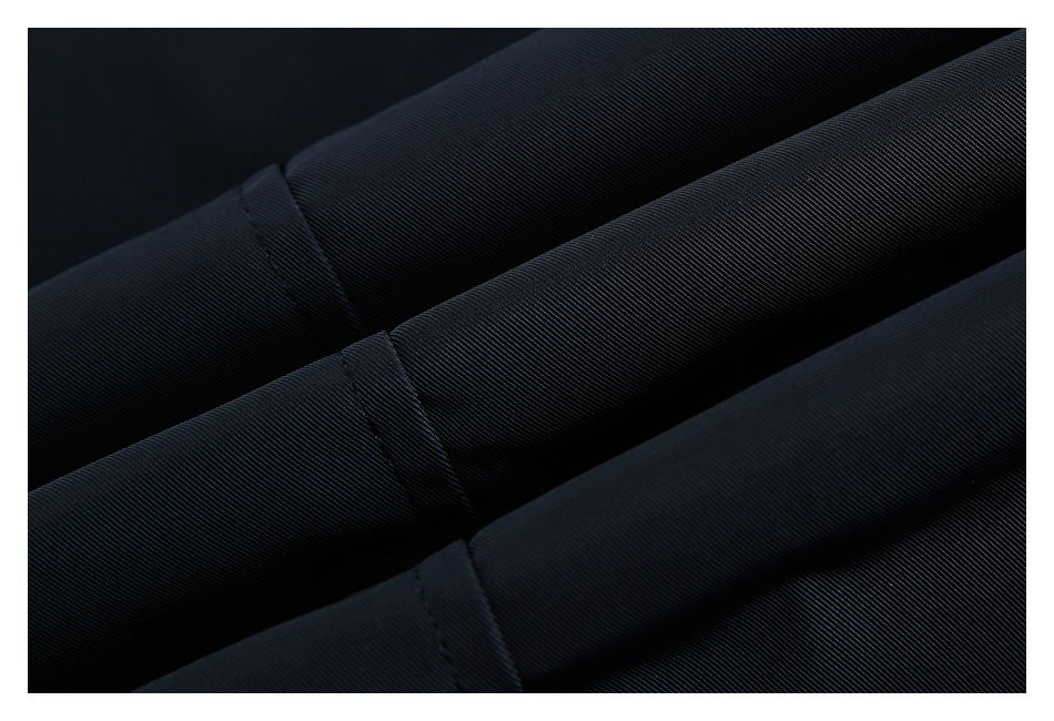 Close-up of folded dark navy fabric showing its fine diagonal weave and stitched seams.