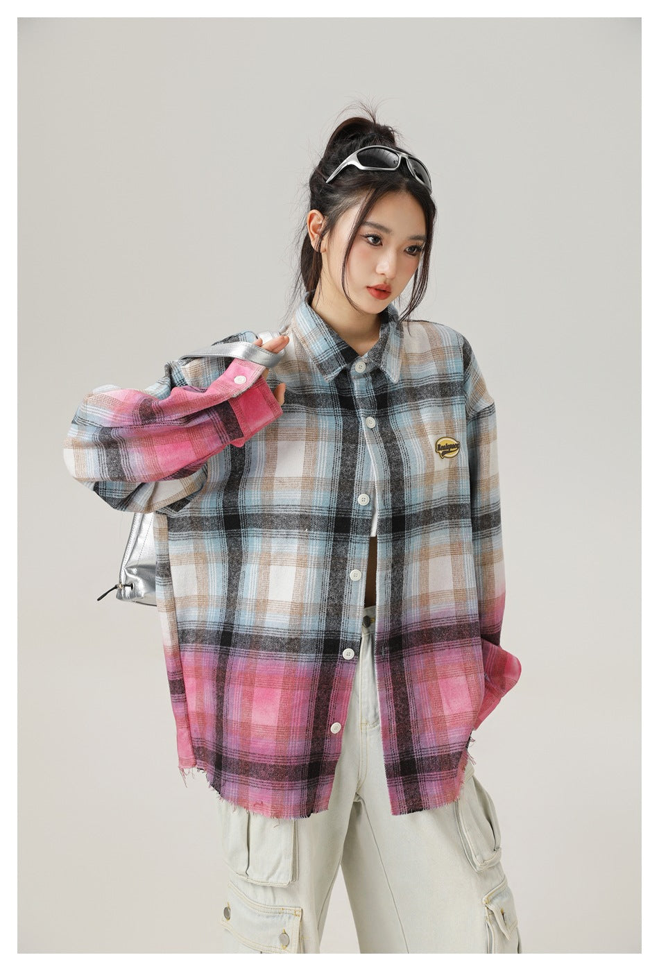 Model wearing an oversized button-up plaid shirt fading from blue, gray and beige to pink, with a chest patch.