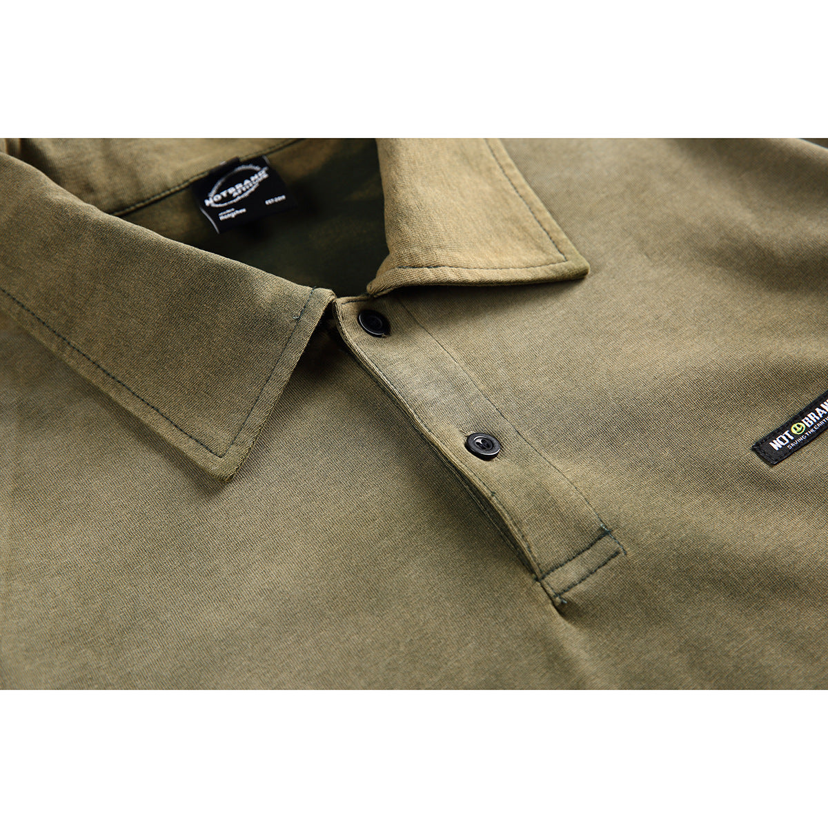 Close-up of an olive short-sleeve shirt collar and two-button placket, with black labels on the neck and chest.