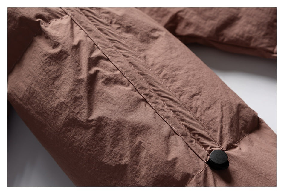 Close-up of a brown garment with a stitched fabric tab and black snap fastener.