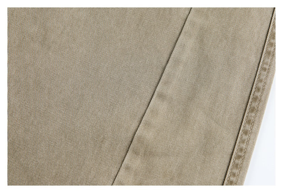 Close-up of the fine diagonal weave and stitched edge of taupe trouser fabric.