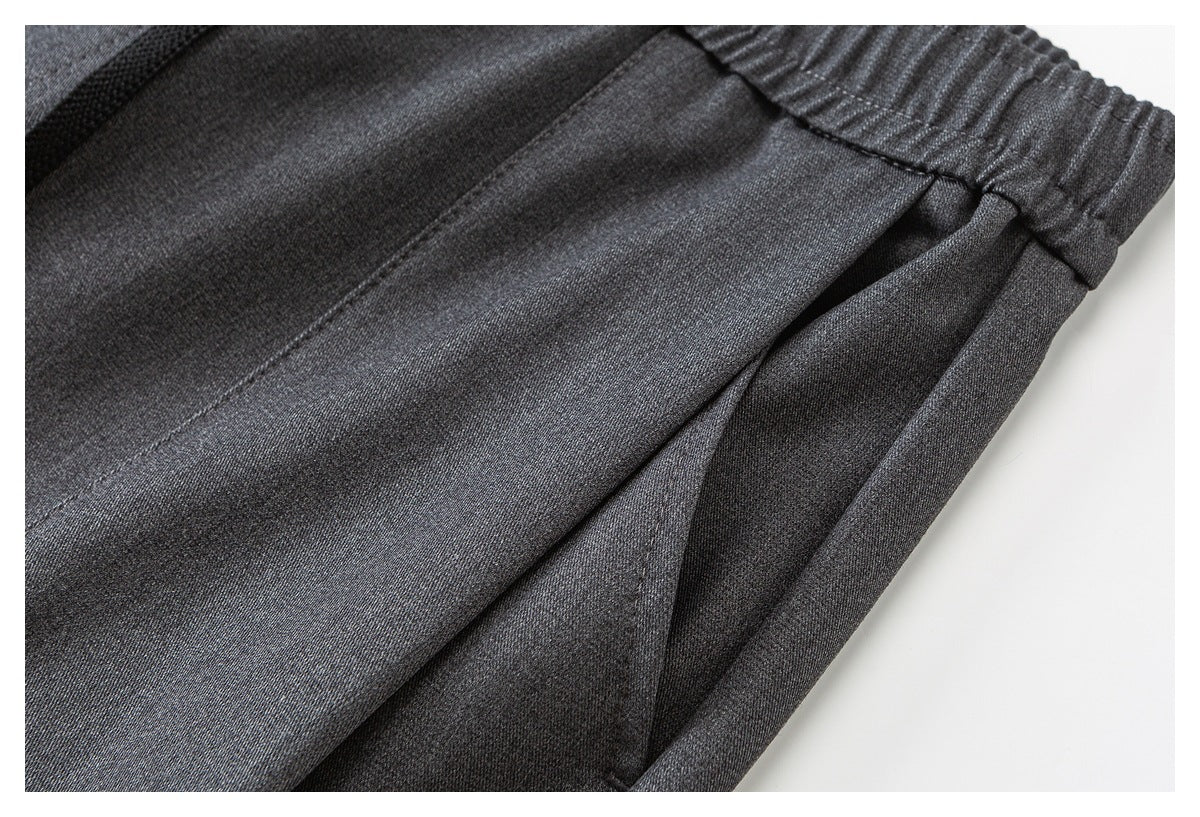 Close-up of charcoal gray pants showing the elastic waistband and a slanted side pocket opening.