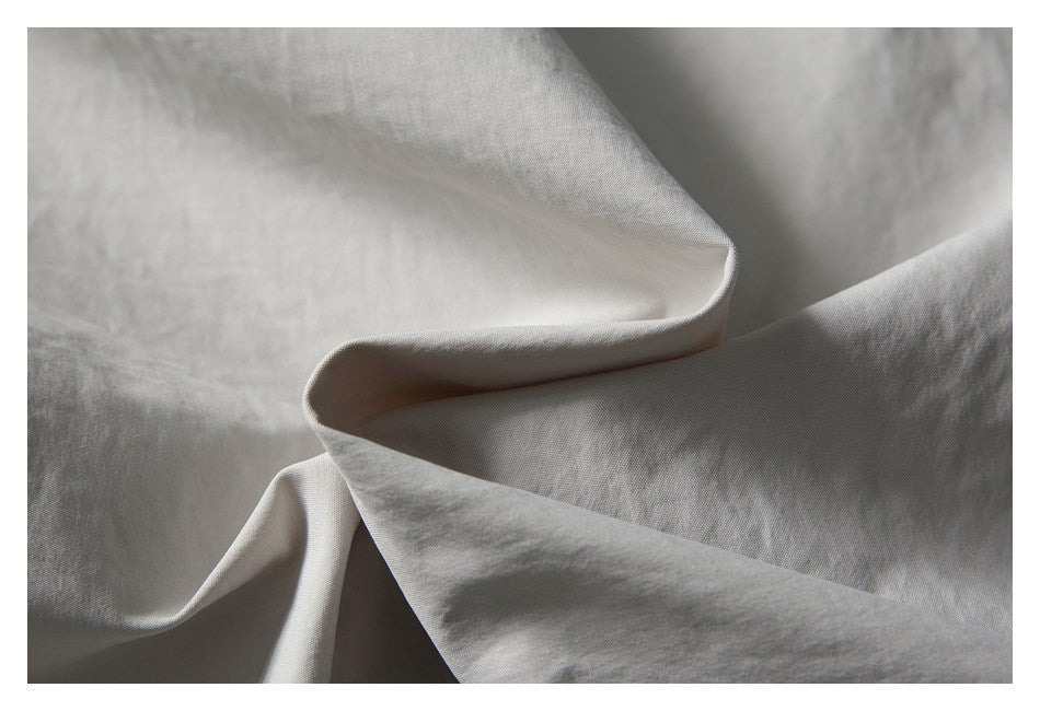 Close-up showing the folds and surface texture of light gray fabric.