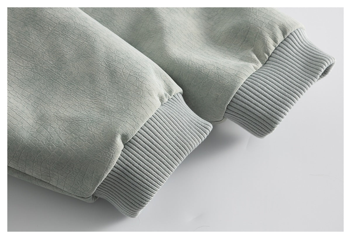 Close-up of two gray ribbed cuffs on sage-green, square-textured garment fabric.