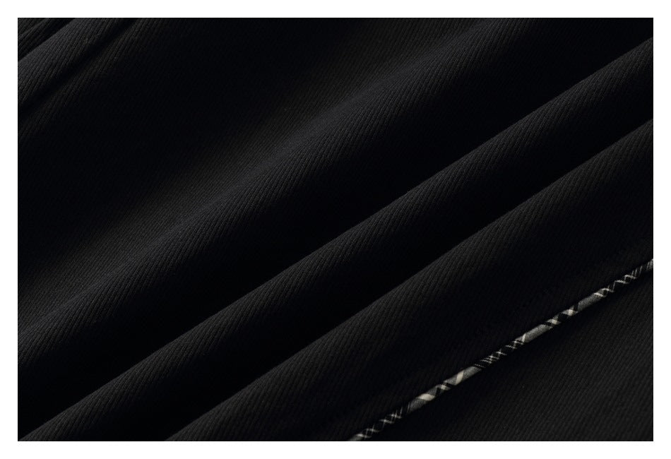 Close-up of black ribbed fabric folds with a narrow light-colored stitched or patterned line.